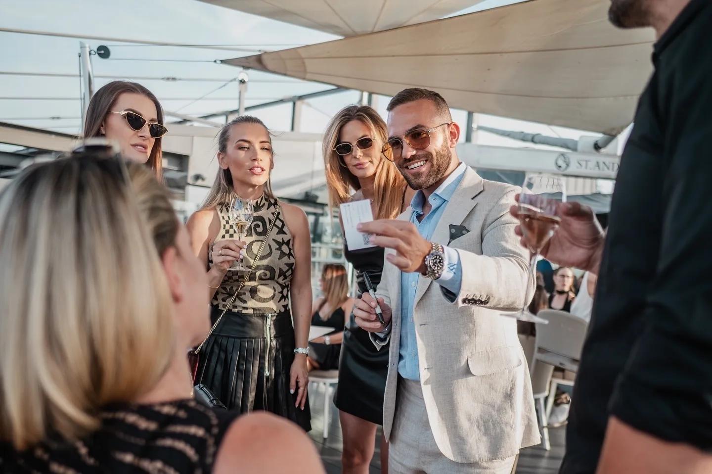 Matteo Cammisa performing close-up magic with a signed card for guests at a rooftop reception