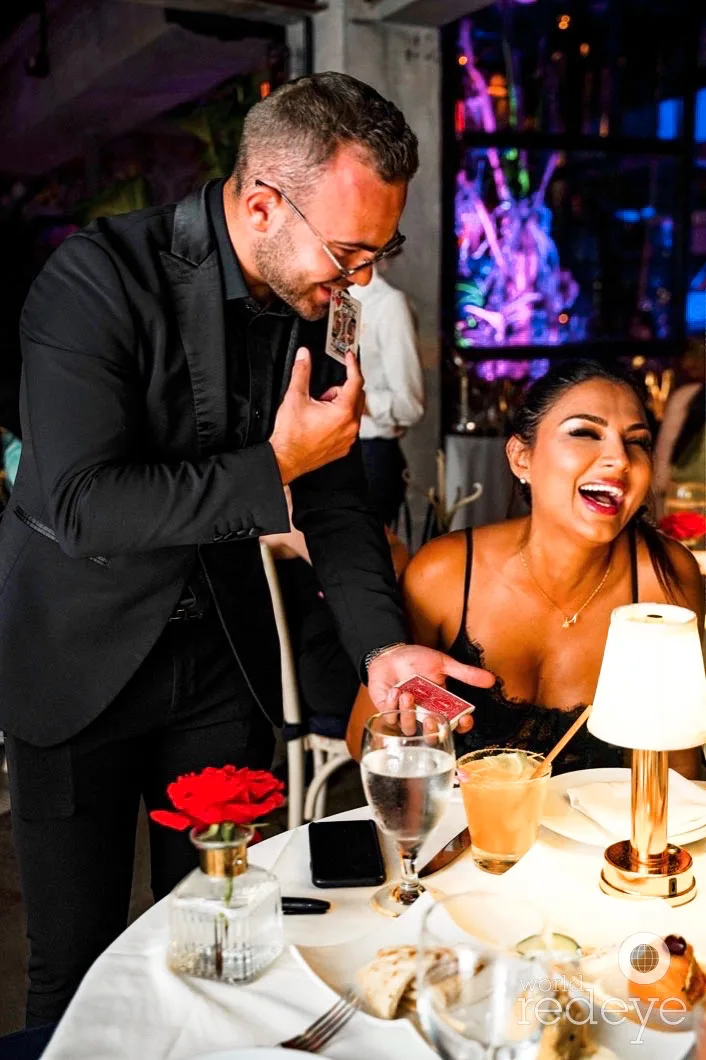 A guest laughing in astonishment during Matteo Cammisa's tableside magic at Kiki on the River