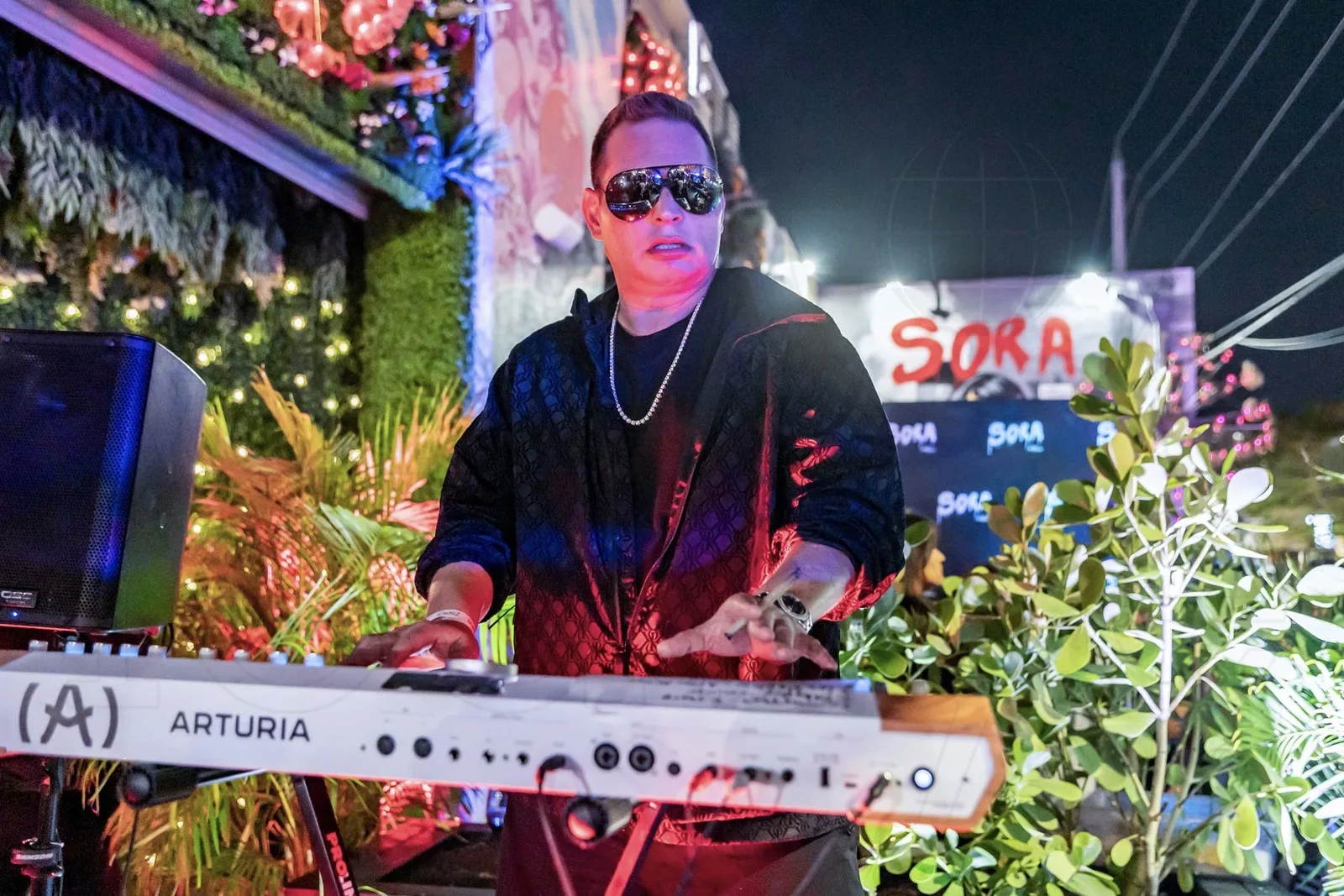 Scott Storch performing beside the illuminated Sora sign in Wynwood