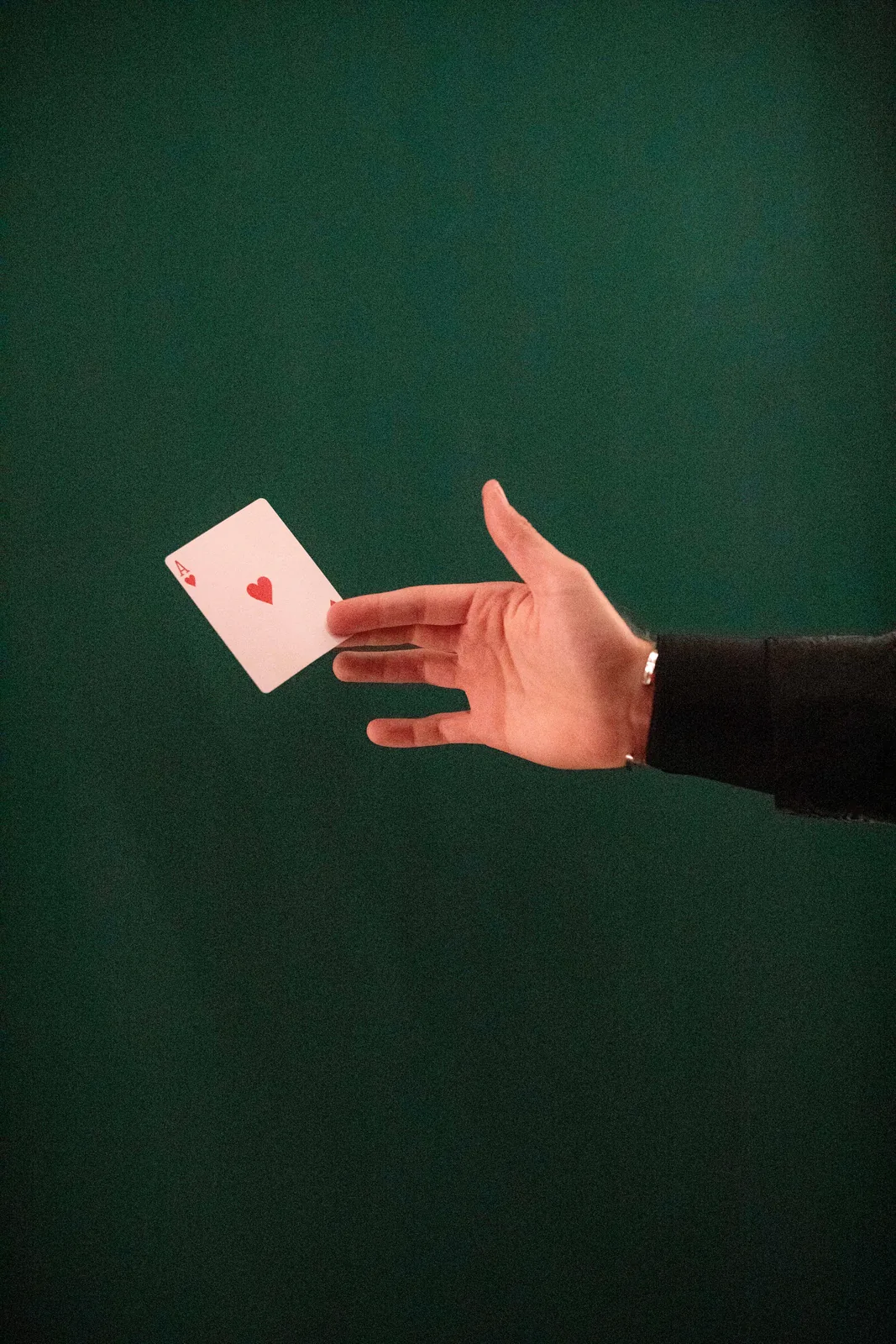 An ace of hearts tossed mid-air against the deep green wall of W Budapest